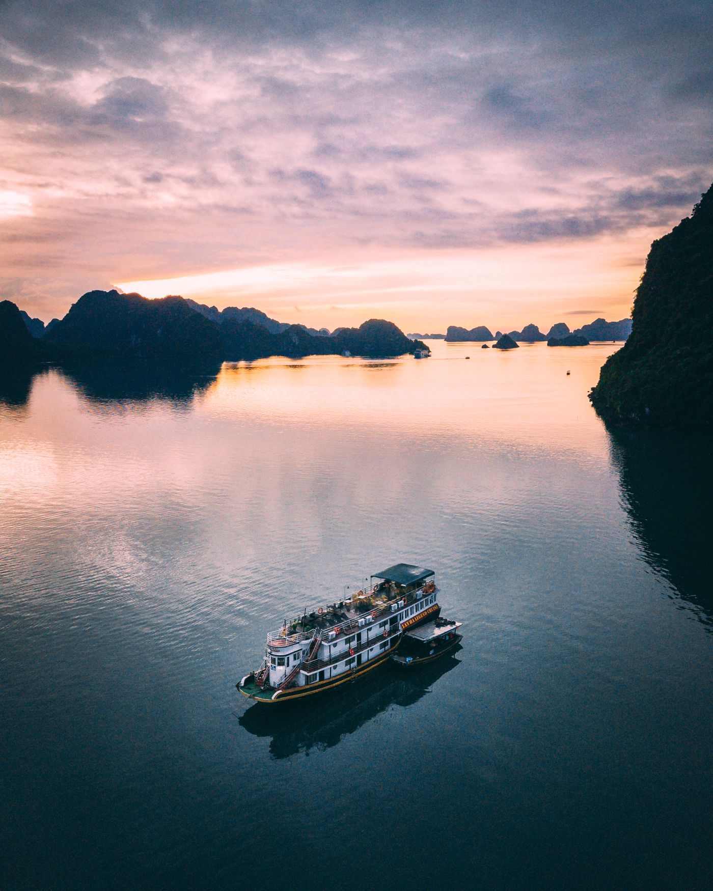 A cruise boat at sunset among the limestone karsts of Ha Long Bay
